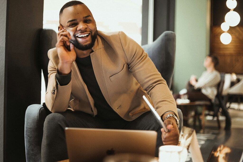 Young professional laughing confidently while working at a cafe, illustrating the career and social benefits of a straight smile