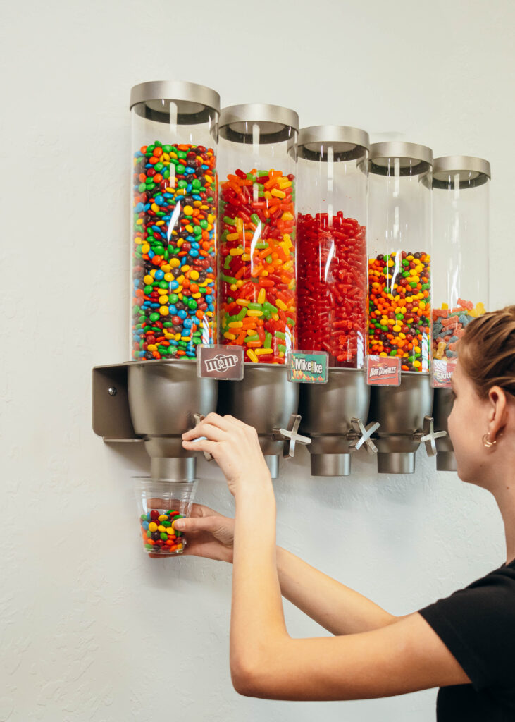 Person getting some sticky candy from a dispenser.