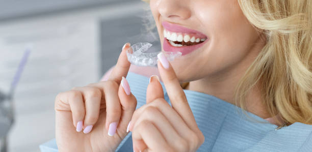 A medium close up of a woman inserting her retainer.