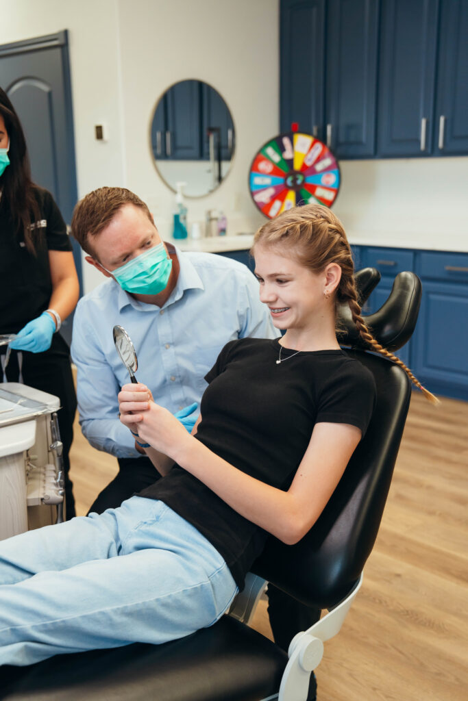 Girl at an orthodontist office looking at her braces in a mirror 