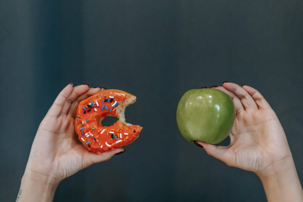 Person choosing between apple and donut showing foods to avoid with braces and sugary food choices during orthodontic treatment
