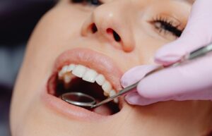 Orthodontist examining patient's crowded teeth and oral health with dental mirror.