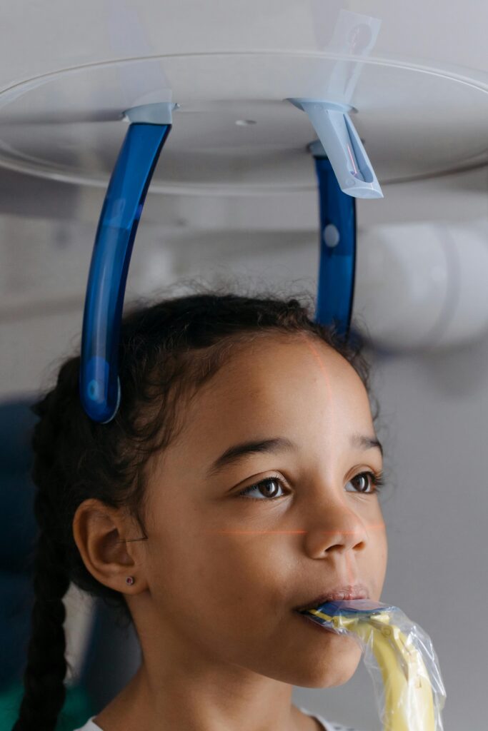 Young girl getting dental X-rays taken at orthodontic appointment to check jaw and teeth development