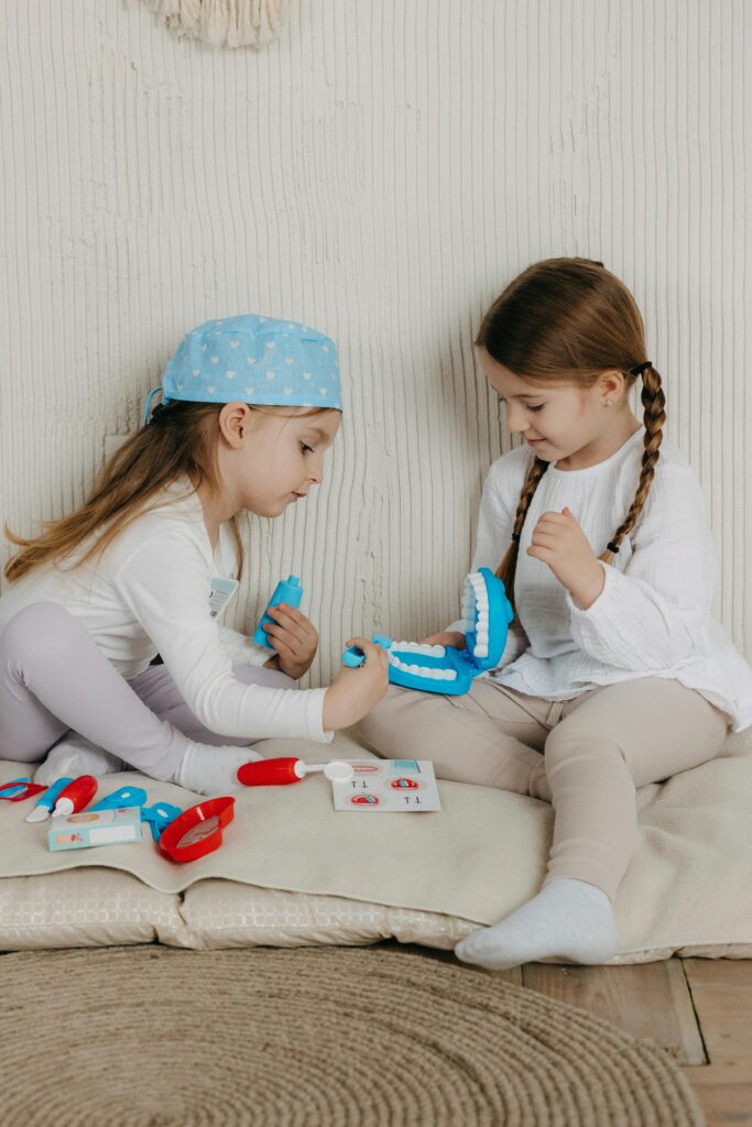 Two children playing pretend orthodontist and examining teeth models to learn about braces