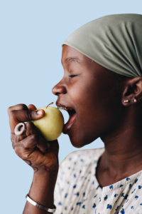Woman with braces biting into a whole apple, illustrating foods to avoid with braces