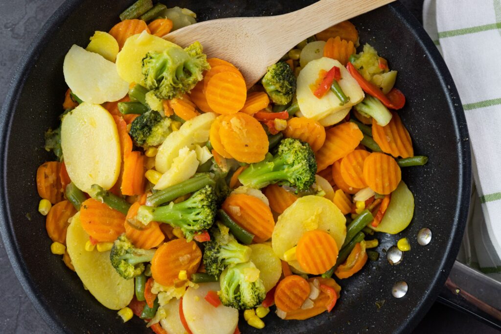 Pan of cooked carrots, broccoli, and mixed vegetables, a safe food option for people with braces