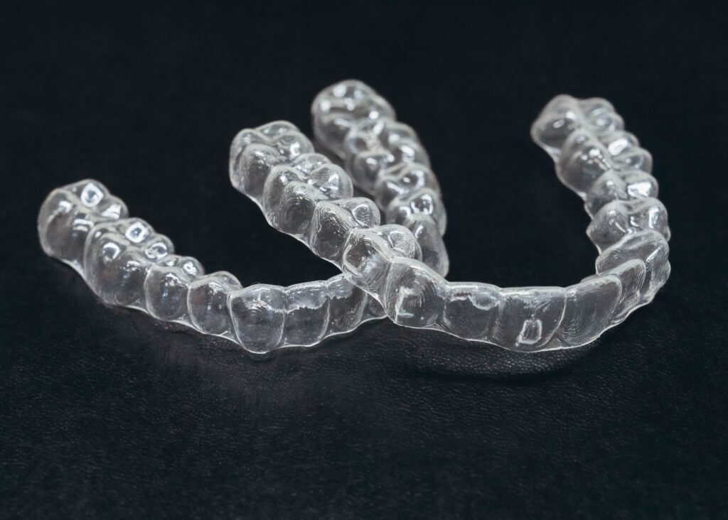 Two clear aligners against a black background at Prince Orthodontics in American Fork, UT