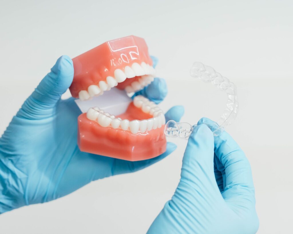 Clear aligner and typodont being held by assistant at Prince Orthodontics in American Fork, UT

